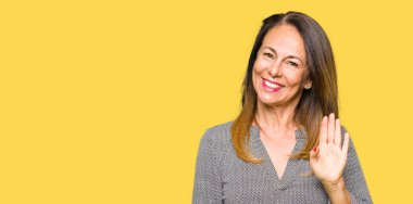 Güzel orta yaş iş kadın Waiving selam söyleyerek mutlu ve gülümseyerek, dostça karşılama jest