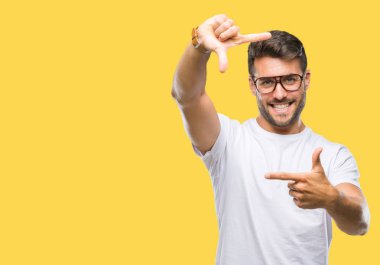 Elle yapma çerçeve ve parmakları ile mutlu yüz gülümseyen izole arka plan üzerinde gözlük takan yakışıklı delikanlı. Yaratıcılık ve Fotoğrafçılık kavramı.