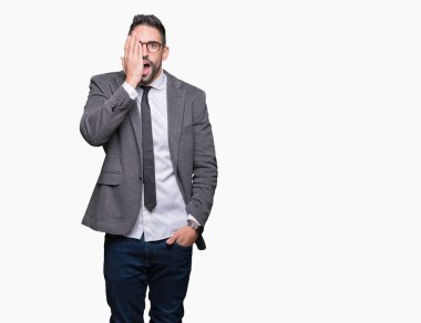Genç yakışıklı iş adamı el yüz ve sürpriz duygu kendinden emin gülümseme ile tek gözüyle kapsayan izole arka plan üzerinde.