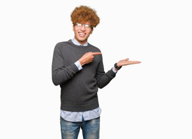 Hayret ve el ile sunulması ve parmak ile işaret ederken kameraya gülümseyen gözlüklü afro saçlı Genç yakışıklı iş adamı.