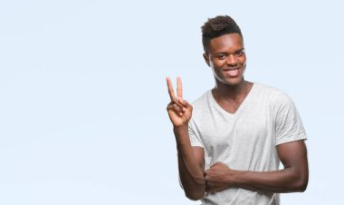 Afrikalı-Amerikalı genç mutlu yüz zafer işareti yaparken kameraya göz kırpıyor ile gülümseyen izole arka plan üzerinde. İki numaralı.