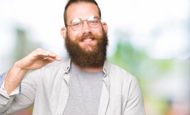 Gözlük ile büyük ve büyük boy işaret, ölçü birimi sembol gösteren el eller genç sarışın adam. Kameraya bakarak gülümsüyordu. Ölçüm kavramı.