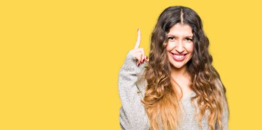 Başarılı fikirle parmağı yukarıyı kış elbise genç güzel kadın. Çıktıktan ve mutlu. Bir numara.