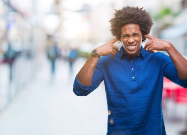Yüksek sesle müzik gürültü rahatsız ifade parmaklarıyla kulaklarıyla kapsayan izole arka plan üzerinde Afro Amerikalı adam. Sağır kavramı.