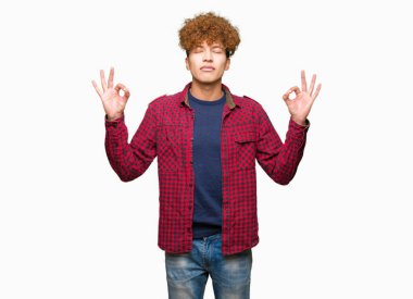 Afro saçlı bir ceket giyen genç yakışıklı öğrenci adam rahatla ve gülümseyen gözlerle kapalı parmak jestle meditasyon yapıyor. Yoga kavramı.