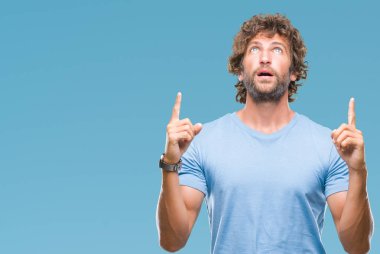 Yakışıklı İspanyol modeli adam izole arka plan üzerinden hayran ve yukarıya bakıp parmakları ile işaret şaşırttı ve silah kaldırdı.