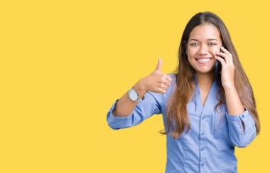 Genç güzel esmer iş kadın Smartphone'da söz arka plan mutlu ok işareti, başparmak ile parmak, mükemmel işareti yapıyor kocaman bir gülümseme ile izole