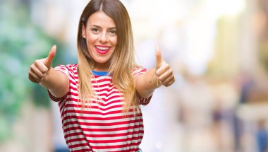 Genç güzel kadın rahat bakmak el ile pozitif jest yapıyor onaylama izole arka plan üzerinde başparmak gülümseyen ve başarı için mutlu. Kamera, kazanan jest arıyorsunuz.