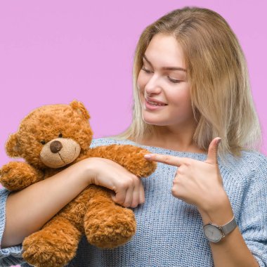 Sevimli Ayıcık izole arka plan üzerinde çok mutlu el ve parmak ile işaret tutan genç beyaz kadın