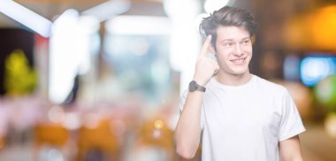 Casual beyaz t-shirt üzerinde izole giyen genç yakışıklı adam arka plan bir parmak, harika bir fikir ya da düşünce, iyi hafıza ile baş gösteren gülen