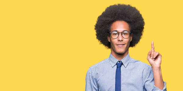 眼鏡をかけて自信を持って 幸せな笑みを浮かべて 指番号のいずれかで上向きの表示とアフロの髪の若いアフリカ系アメリカ人ビジネス男 — ストック写真
