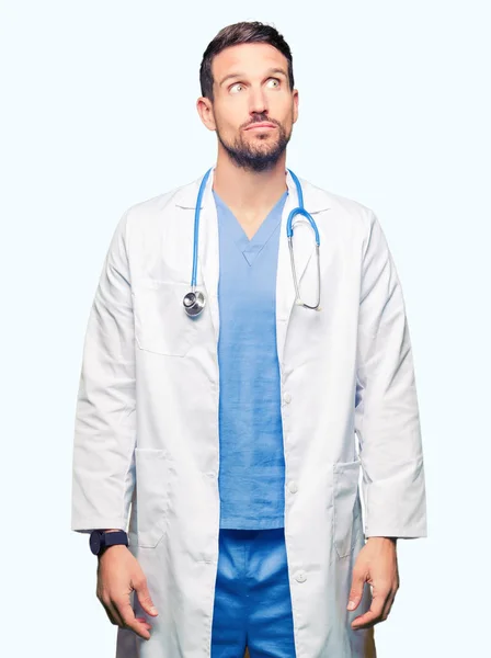 英俊的医生人穿着医疗制服在孤立的背景微笑看边和盯着看的想法 — 图库照片