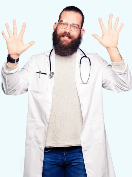 若いブロンド医師男性でひげを示す医療の着用のコートと自信を持って 幸せな笑みを浮かべている間 の指で上向き数 — ストック写真