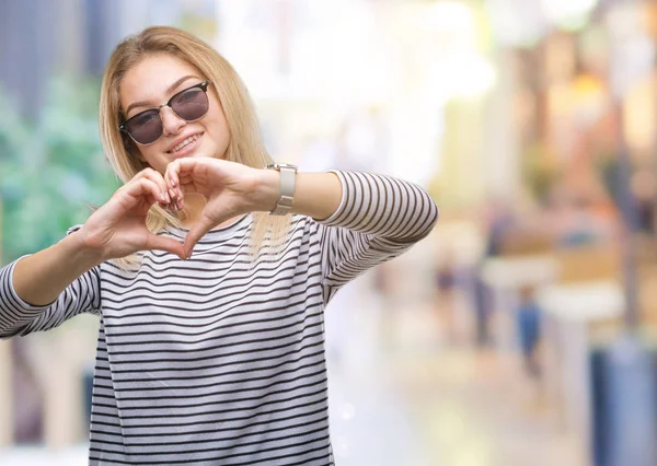 年轻的白种女人戴墨镜在孤立的背景微笑的爱显示心脏符号和形状用手 浪漫概念 — 图库照片