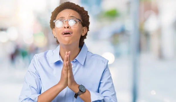 Young beautiful african american business woman over isolated background begging and praying with hands together with hope expression on face very emotional and worried. Asking for forgiveness. Religion concept.