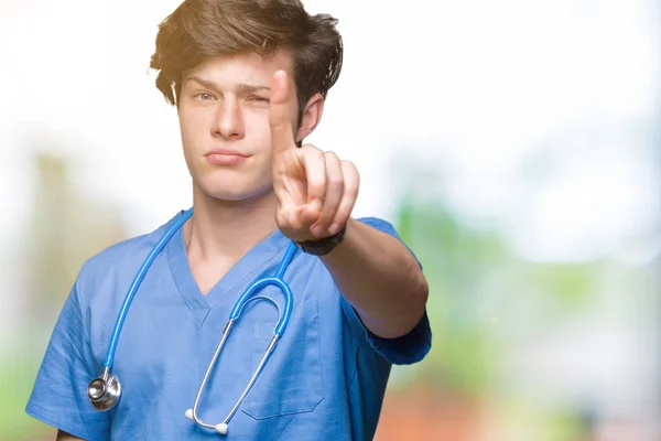 年轻的医生穿着医疗制服在孤立的背景指向用手指和愤怒的表情 — 图库照片