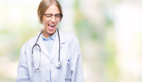 美丽的年轻金发碧眼的医生妇女穿着医疗制服在孤立的背景眨眼看着相机与性感的表情 欢快和快乐的脸 — 图库照片