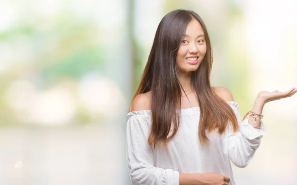 陽気な提示とカメラを見て手の手のひらで指している笑みを浮かべて孤立の背景の上の若いアジア女性 — ストック写真