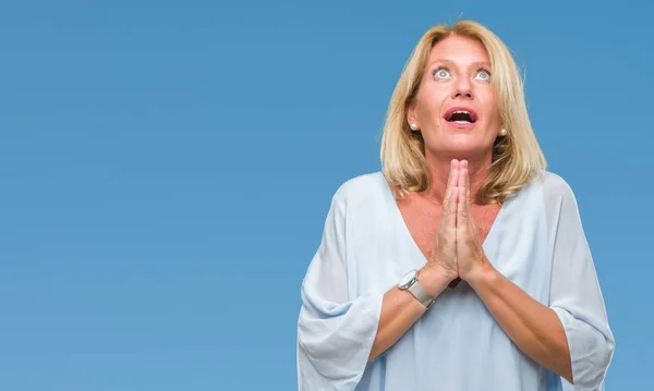 Middle age blonde business woman over isolated background begging and praying with hands together with hope expression on face very emotional and worried. Asking for forgiveness. Religion concept.