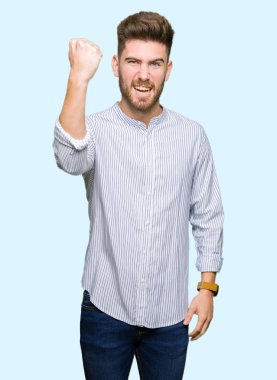 Öfkeyle bağırırken sinirli ve öfkeli genç ve yakışıklı bir adam yumruk kaldırıyor. Öfke ve agresif kavram.