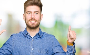 Gösterilen ve parmakları ile işaret rahat kot gömlek giymiş genç yakışıklı sarışın adam kendinden emin ve mutlu gülümseyerek süre 6 numara.