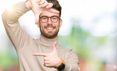 Elle yapma çerçeve ve parmakları ile mutlu yüz gülümseyen gözlüklü genç yakışıklı iş adamı. Yaratıcılık ve Fotoğrafçılık kavramı.