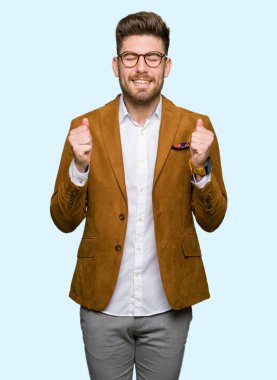 Silah ile başarı için heyecanlı gözlüklü genç yakışıklı iş adamı zafer kutluyor gülümseyen kaldırdı. Kazanan kavramı.