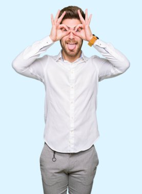 Genç yakışıklı iş adamı, dilini parmaklarının arasından baktığını yapışmasını dürbün gibi ok jest yapıyor. Deli ifade.