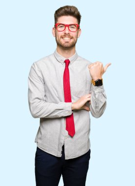 Seyir ve başparmak yanında yukarıyı mutlu yüz ile gülümseyen gözlüklü genç yakışıklı iş adamı.