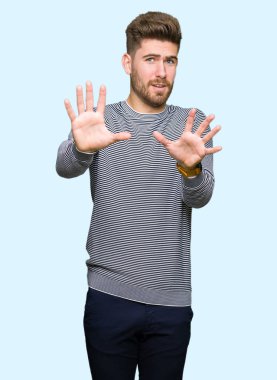 Şokta bağırarak çizgili süveter korkuyor ve korku ifade dur hareketi el ile ile dehşete giyen genç yakışıklı adam. Panik kavramı.