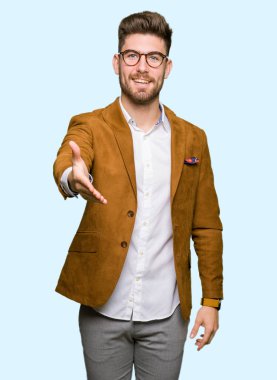 Tebrik ve konuksever dost sunan karşılıklı gülümseyen gözlüklü genç yakışıklı iş adamı. Başarılı iş.