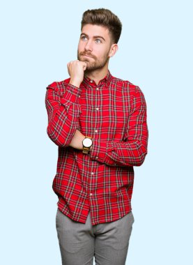 Yakışıklı delikanlı çene düşünme hakkında soru, dalgın ifade üzerine el ile. Düşünceli yüzüyle gülümsüyor. Şüphe kavramı.