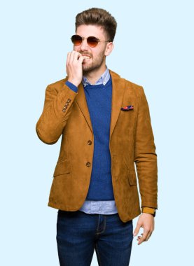 Genç yakışıklı zarif adam stresli ve gergin ile güneş gözlüğü takıyor tırnak ısırma dudaklarından eller. Anksiyete sorunu.