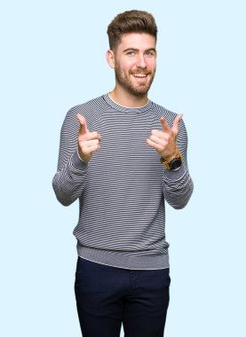 Çizgili süveter işaret parmak kamera ile mutlu ve komik yüz giyen genç yakışıklı adam. İyi enerji ve vibes.