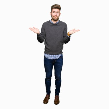 Genç yakışıklı zarif adam clueless ve şaşkın ifadeyle kollar ve eller kaldırdı. Şüphe kavramı.