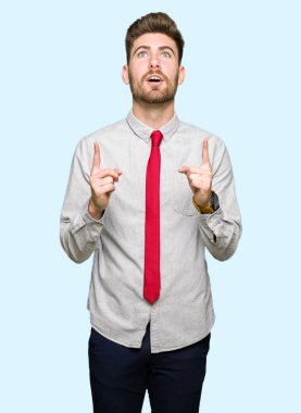 Genç yakışıklı iş adamı şaşırtmak ve yukarıya bakıp parmakları ile işaret şaşırttı ve silah kaldırdı.