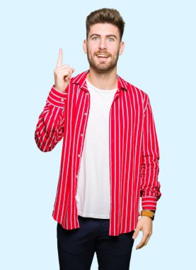 Genç yakışıklı başarılı fikirle giyen kırmızı gömlek işaret parmağı adam. Çıktıktan ve mutlu. Bir numara.