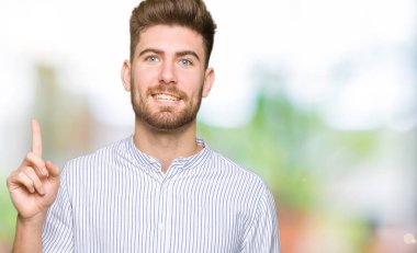 Genç yakışıklı adam başarılı bir fikirle işaret ediyor. Heyecanlı ve mutlu. Bir numara..