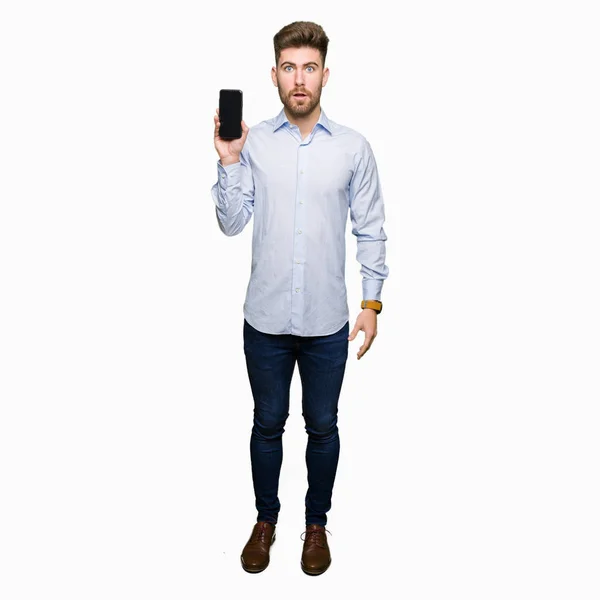 年轻英俊的男人企业显示智能手机屏幕吓得惊讶与一个惊喜的脸 害怕和兴奋的恐惧表情 — 图库照片