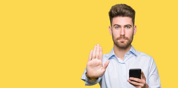 年轻英俊的男人业务使用智能手机与开放的手做停止标志与严肃和自信的表情 防御手势 — 图库照片