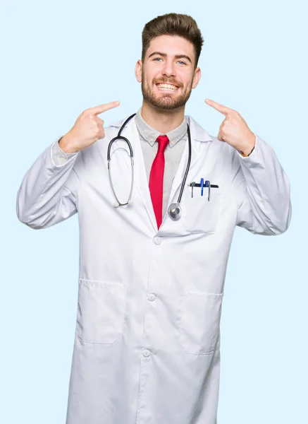若いハンサムな医者男は自信を示すと指歯と口を指して笑って医療のコートを着ています 健康の概念 — ストック写真