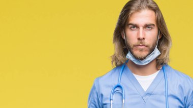 Genç yakışıklı Doktor adam yüzünde ciddi bir ifade ile izole arka plan üzerinde uzun saçlı. Basit ve doğal kameraya bakıyor.