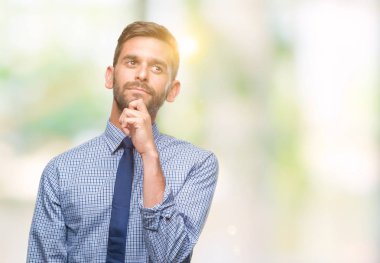 Genç yakışıklı iş adamı çene düşünme hakkında soru, dalgın ifade üzerine el ile izole arka plan üzerinde. Düşünceli yüzüyle gülümsüyor. Şüphe kavramı.
