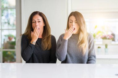 Anne ve kızı birlikte esneme sıkılmış evde güzel ailesinin kapsayan ağız el ile yorgun. Restless ve uyku hali.