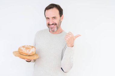 Komuta sizde işaret ve başparmak kadar mutlu yüz gülümseyen tarafı ile gösteren izole arka plan üzerinde ev yapımı taze ekmek tutan