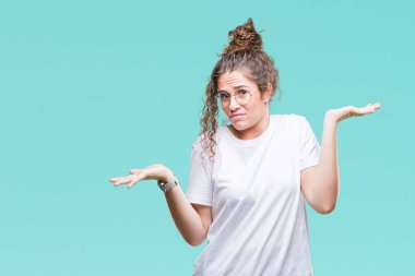 Güzel genç esmer kıvırcık saçlı kız gözlüklü üzerinde arka plan clueless ve şaşkın bir ifadeyle kollar ve eller kaldırdı izole. Şüphe kavramı.