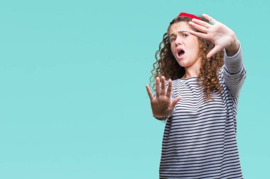 Güzel esmer kıvırcık saçlı Genç kız giyiyor kazak korkuyor ve dehşet korku ifade dur hareketi el ile ile izole arka plan üzerinde şok bağırarak çizgili. Panik kavramı.