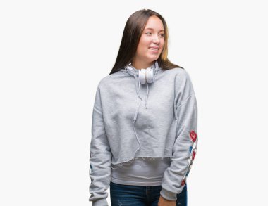 Üzerinde kulaklık giyen genç güzel beyaz öğrenci kadın arka plan uzak tarafına gülümseme ile yüzünde, doğal ifade arıyorum izole. Kendine güvenen gülüyor.