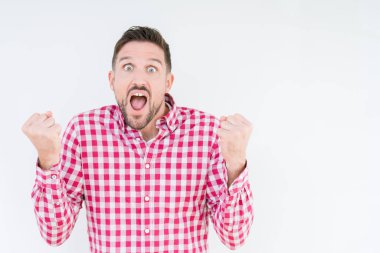 Yakışıklı delikanlı izole arka plan kutlama üzerinde gömlek giymiş şaşırttı ve başarı için kaldırdı kollarını açarak hayret ve gözleri açık. Kazanan kavramı.