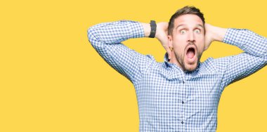 Yakışıklı iş adamı mavi ile deli gözleri ve elleri baş, korkuyor ve açık ağzı ile şok sürpriz korkuttu